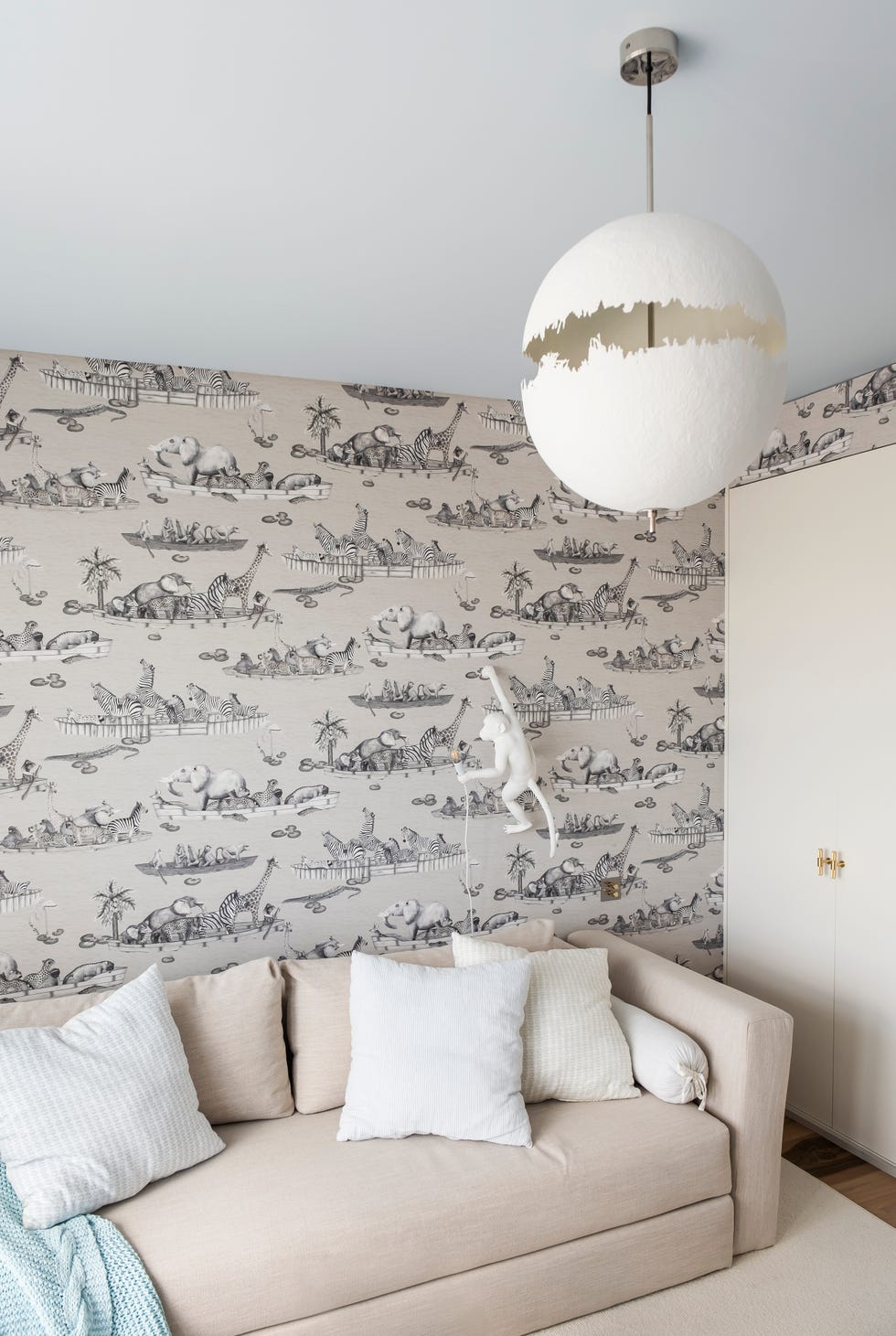 zona de juegos infantil con papel pintado de animales y sofá cama beige