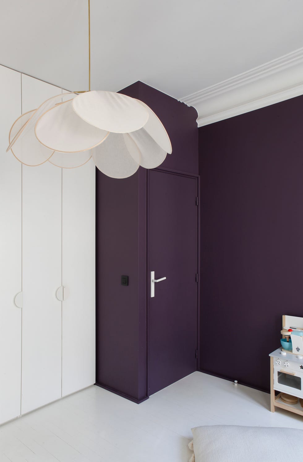 habitación con puerta y pared en morado y lámpara con pantalla de pétalo