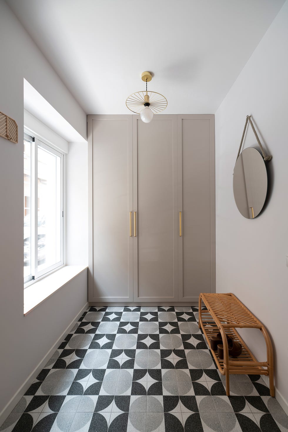 recibidor mid century con banco de ratán, armario empotrado gris y suelo con baldosas geométricas