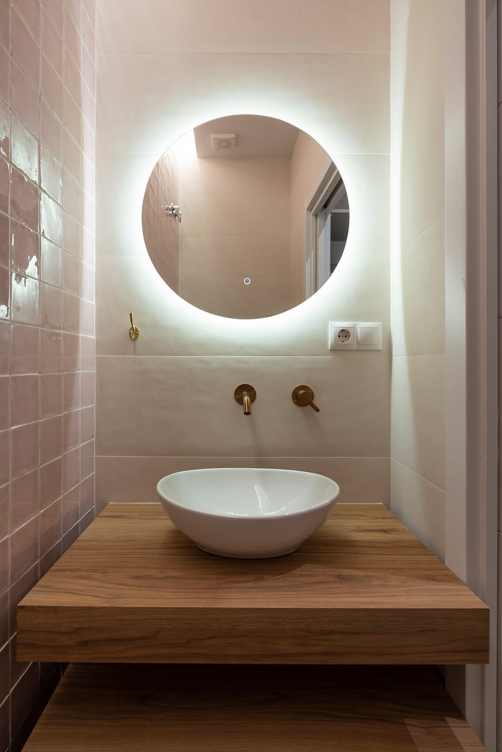 baño de estilo retro con azulejos rosas y mueble de madera