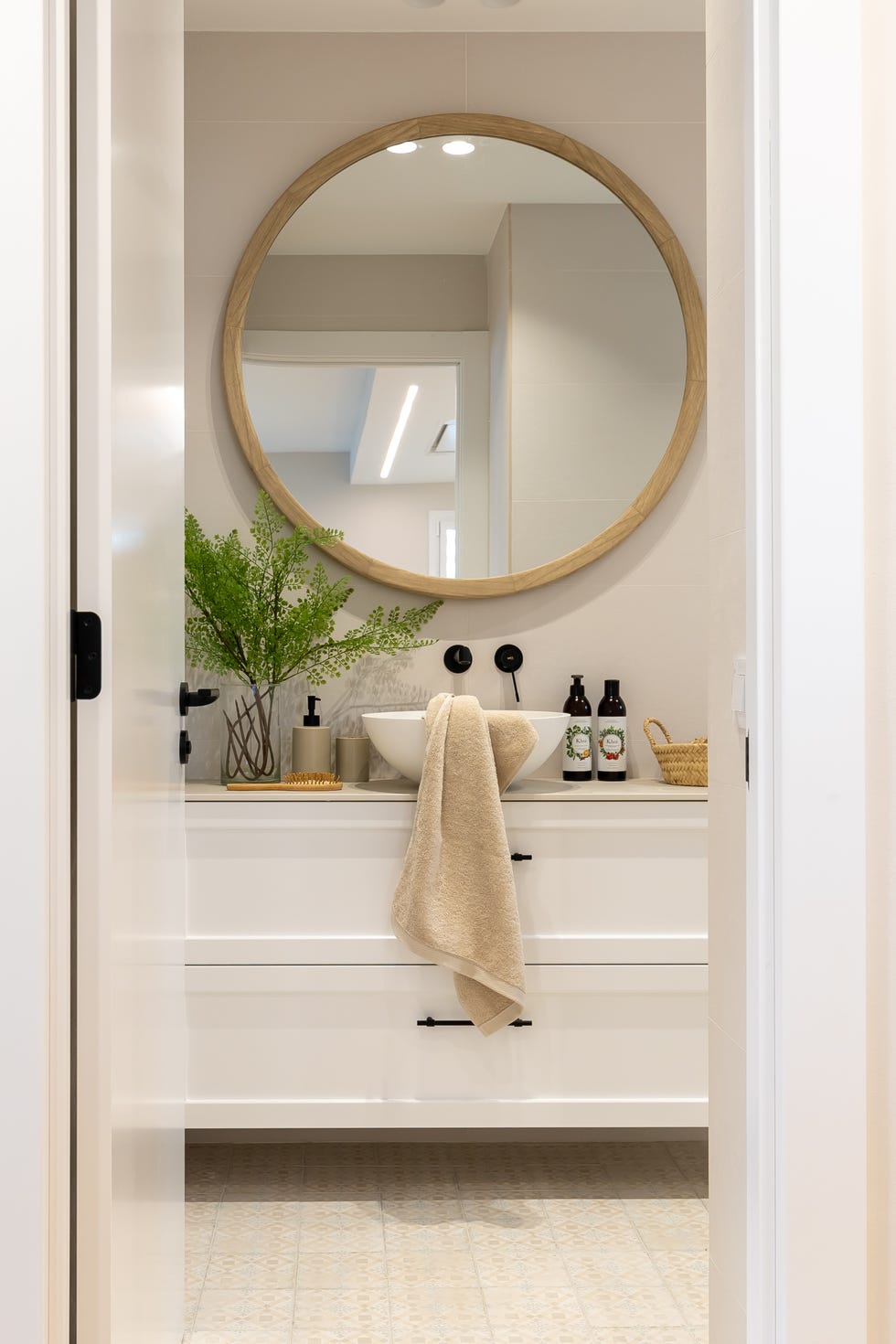 baño con mueble blanco volado y espejo redondo
