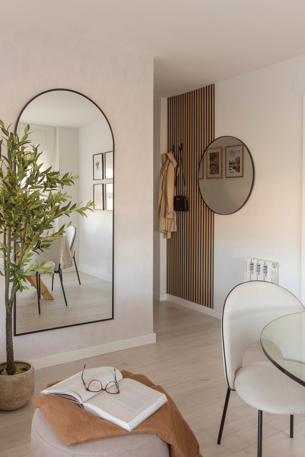 espejo de pared con forma oval y al fondo revestimiento de palillería