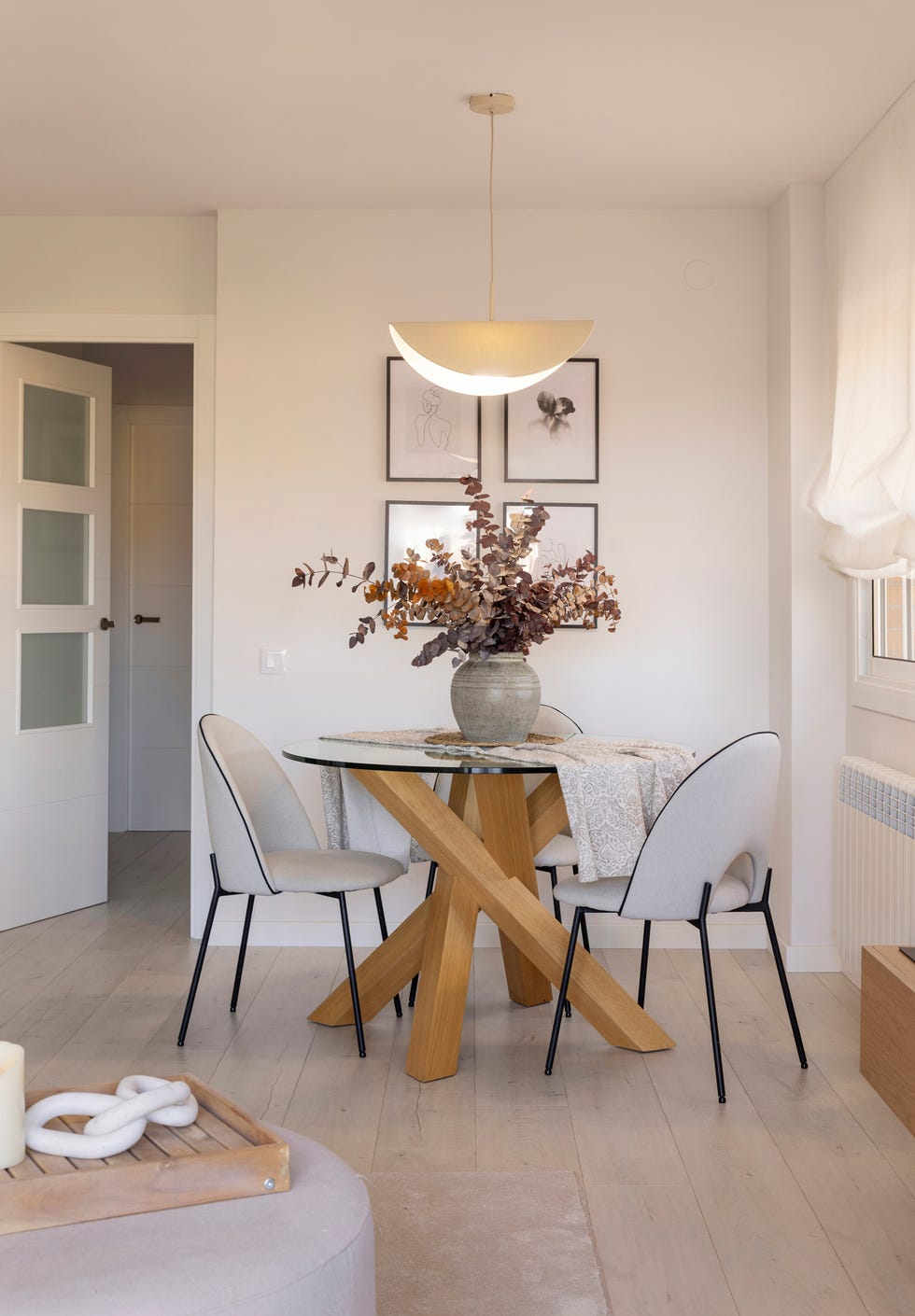 mesa de comedor con sobre redondo de cristal y base de madera