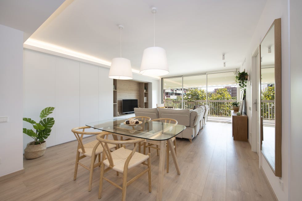 comedor con mesa de madera y cristal, sillas wishbone y lámpara de techo blanca