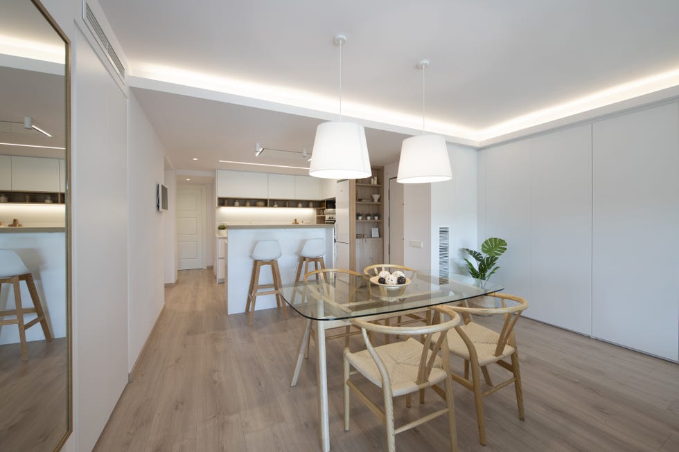 comedor con mesa de madera y cristal, sillas wishbone y lámpara de techo blanca