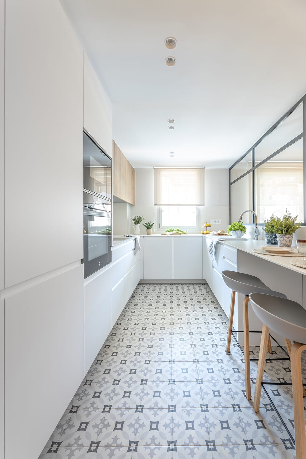 cocina moderna con armarios blancos y barra de desayuno con taburetes
