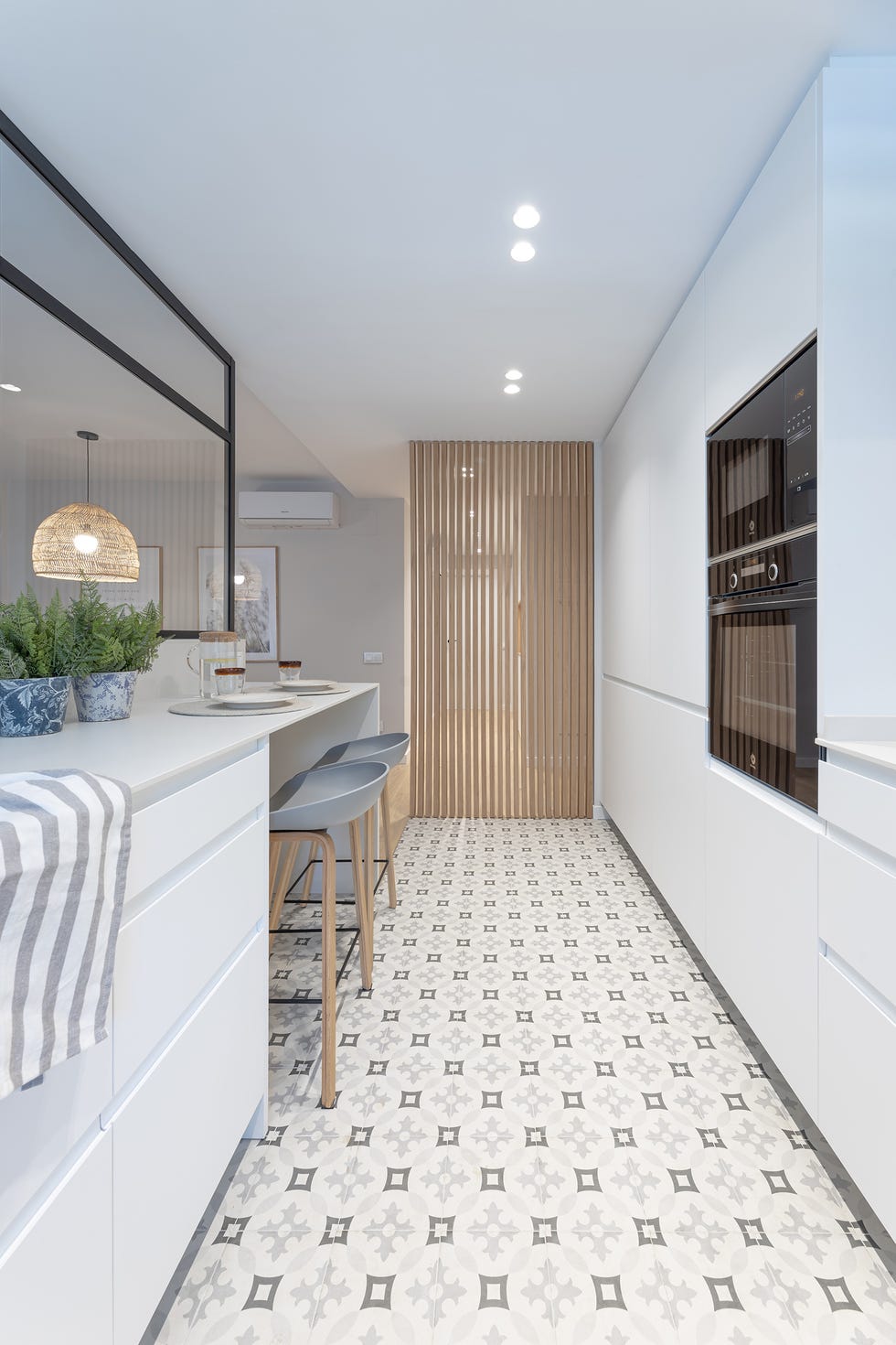 cocina moderna con armarios blancos y barra de desayuno con taburetes