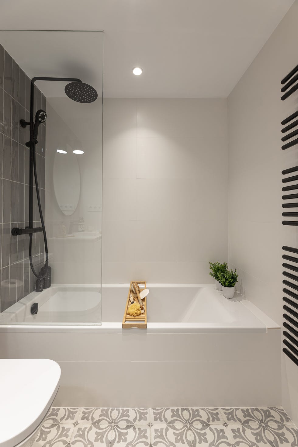 baño moderno con bañera, suelo de baldosas hidráulicas y pared con azulejos grises