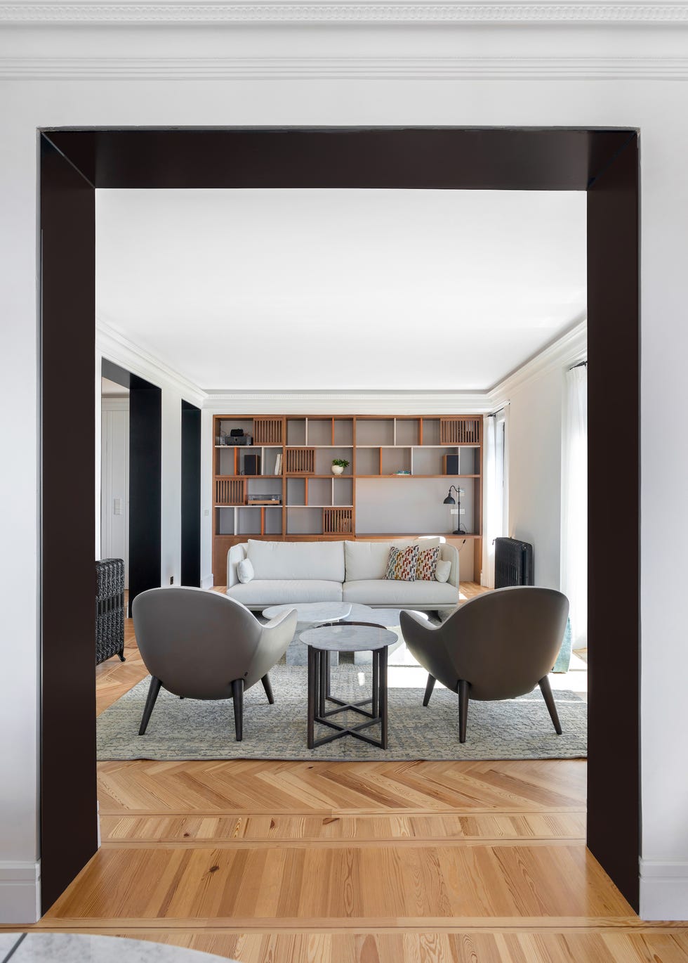 salón moderno con dos butacas, sofá y librería de madera a medida con escritorio
