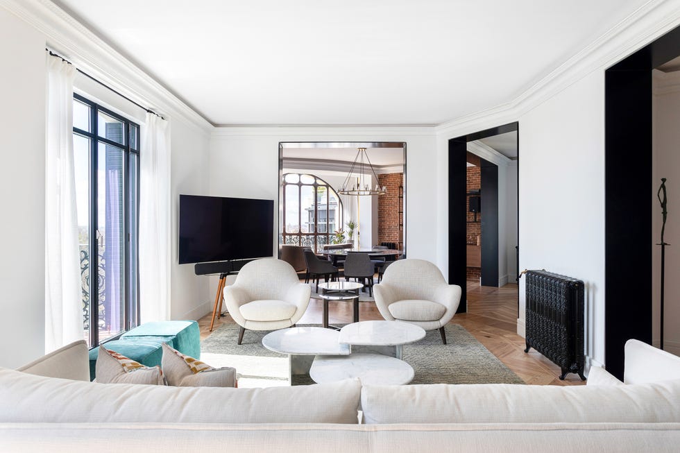 salón abierto de diseño moderno con sofá, mesas de centro de mármol y dos butacas