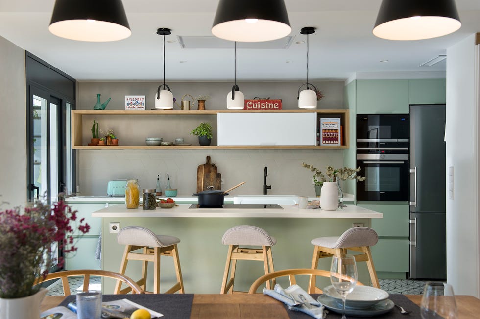 Cocina con isla central y barra de desayunos decorada en verde empolvado