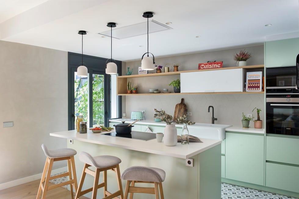 Cocina con isla central y barra de desayunos decorada en verde empolvado