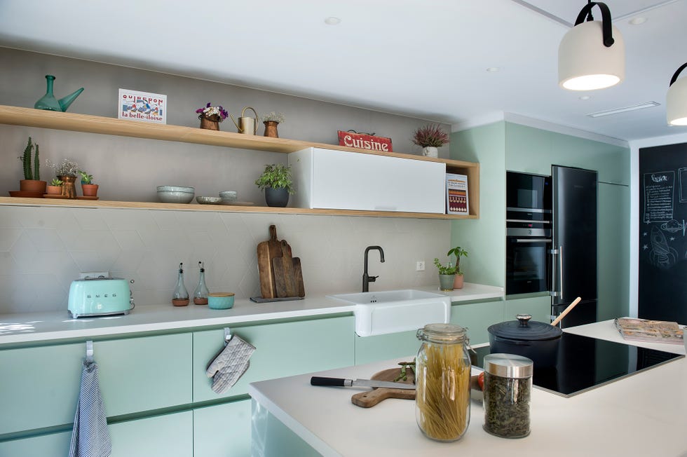Cocina con isla central y barra de desayunos decorada en verde empolvado