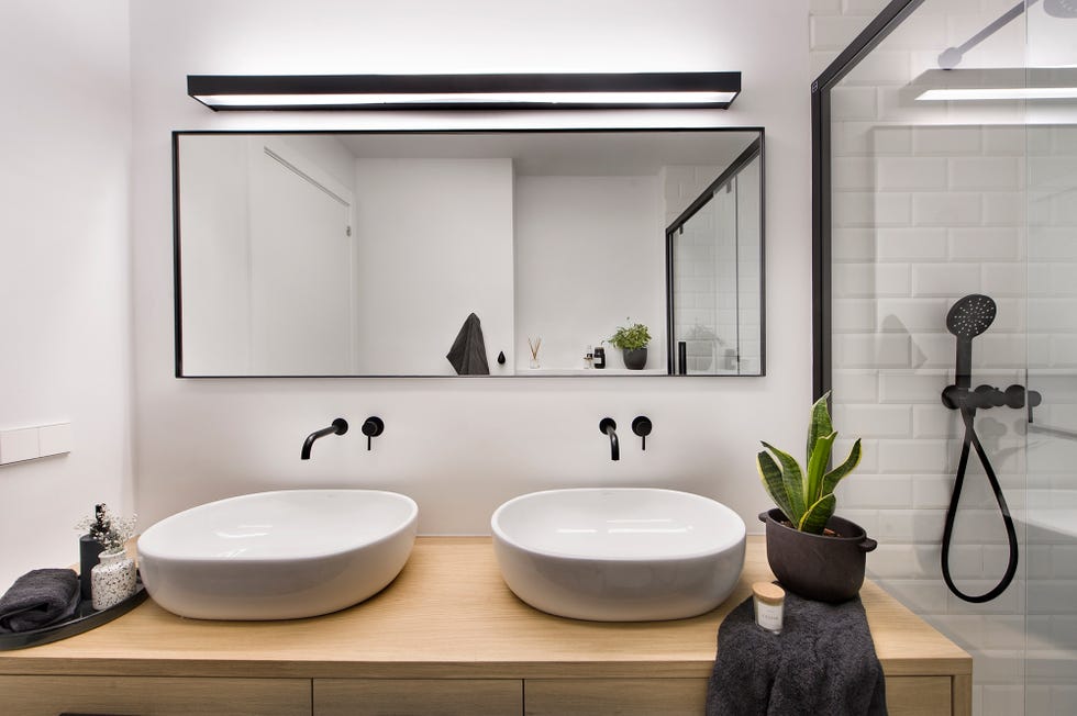 Lavamanos blancos sobre un mueble de madera y grifería negro mate