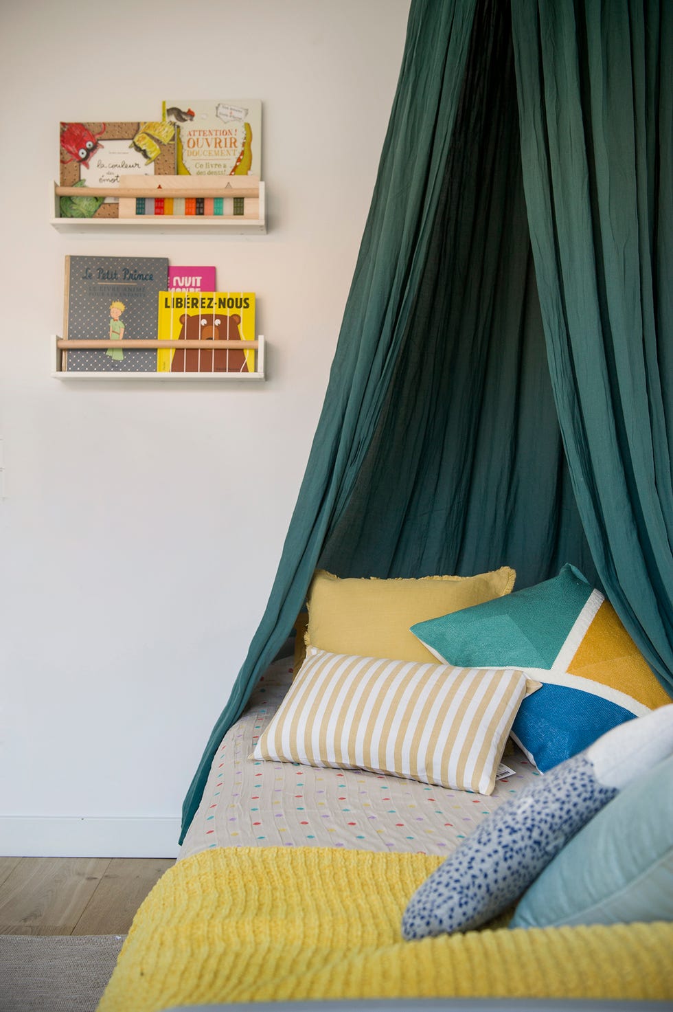 Detalle de la cama infantil con cojines de colores y dosel verde
