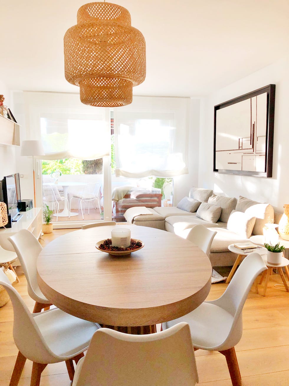 mesa de comedor de madera ovalada, sillas blancas y lámpara de fibras