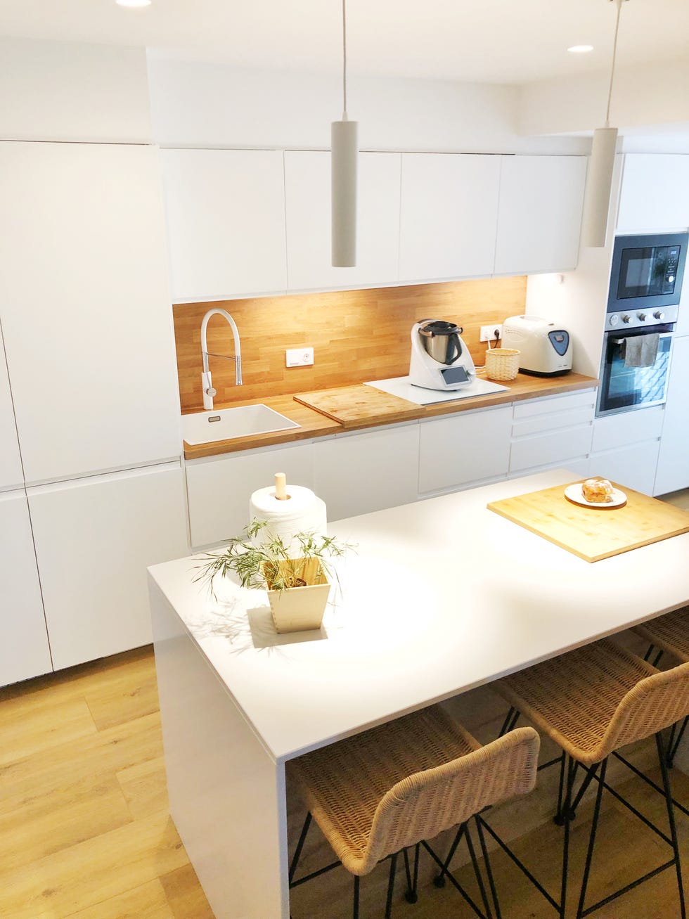 cocina blanca con isla central, taburetes de fibras y encimera y frente de madera