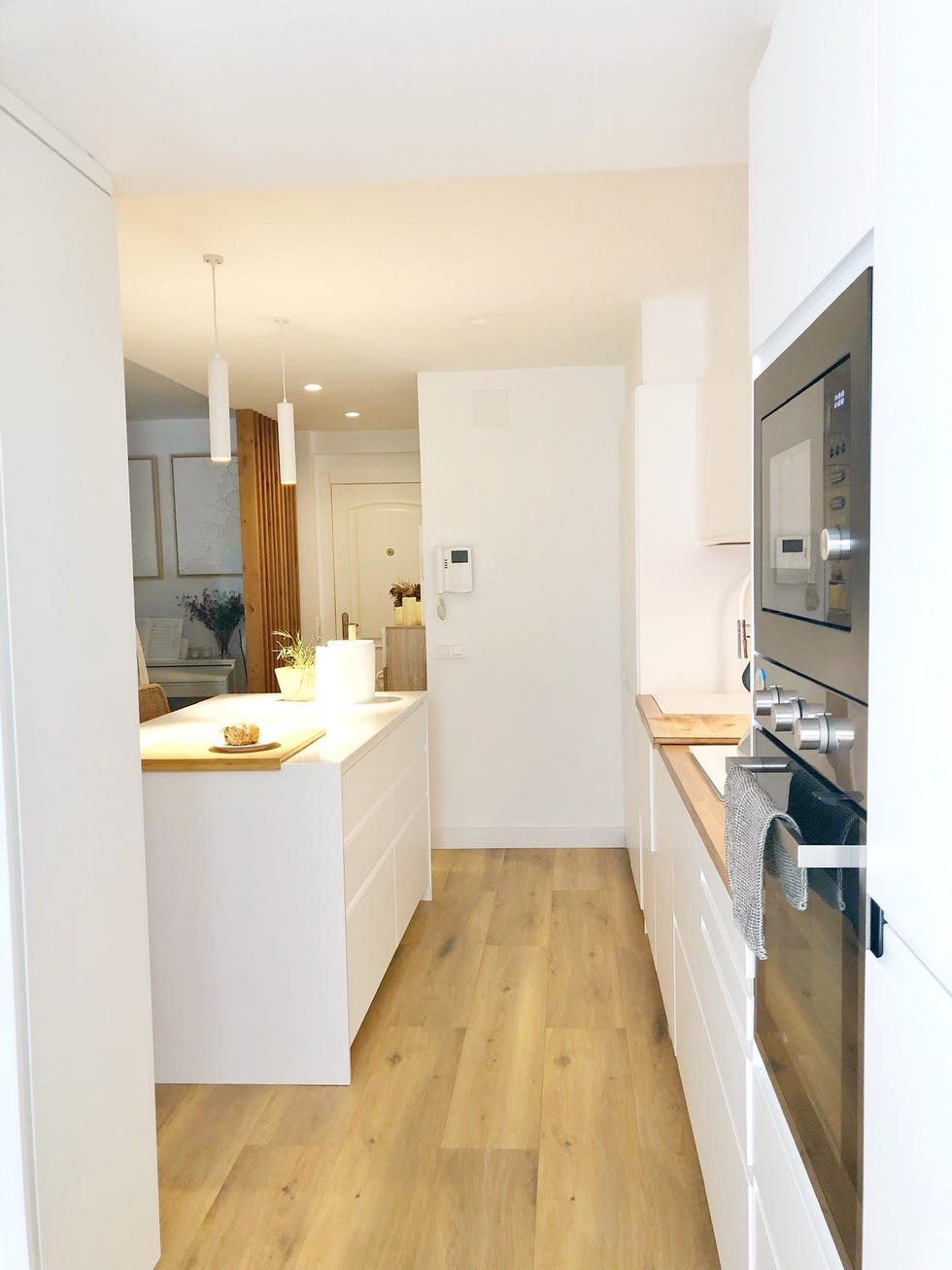 cocina blanca con isla central y encimera de madera