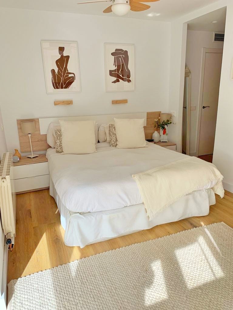 dormitorio de estilo boho con cabecero de madera y mesitas en blanco y madera