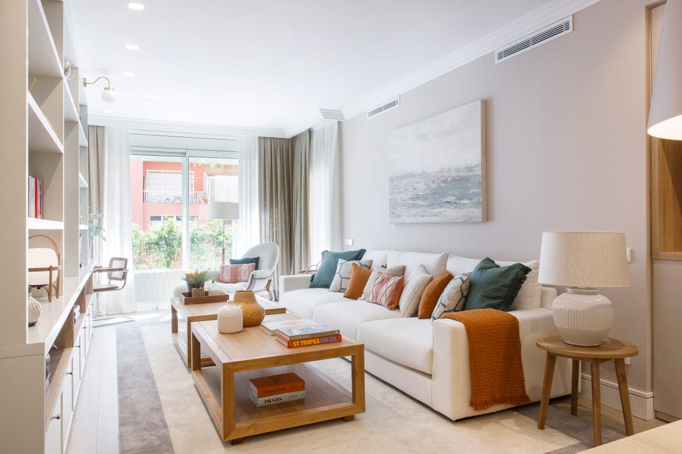 salón con sofá blanco, mesas de centro de madera y estantería blanca a medida
