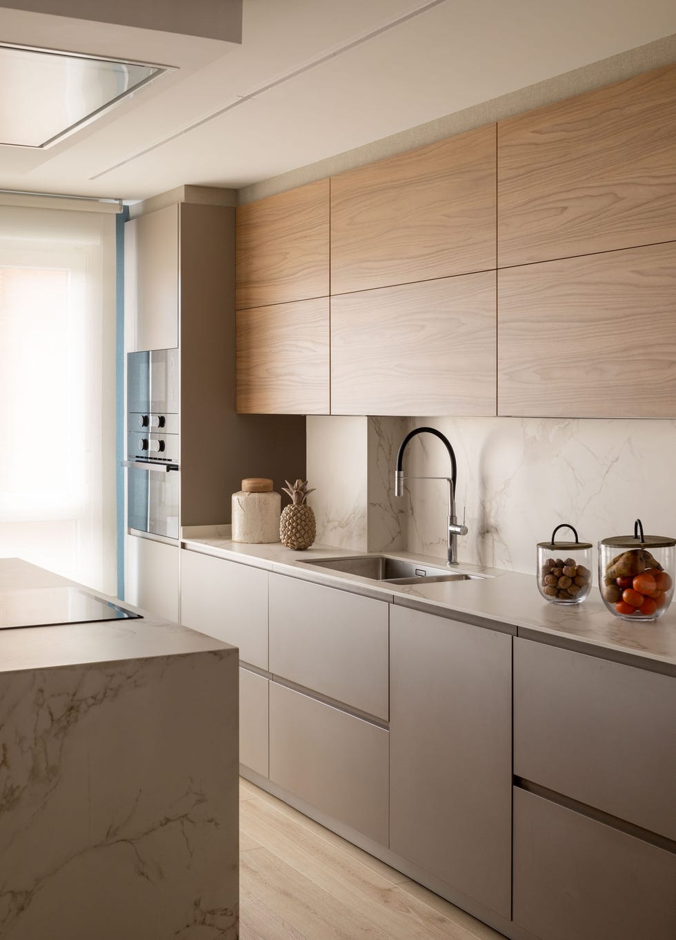 cocina con isla y frentes que combinan el color topo y la madera