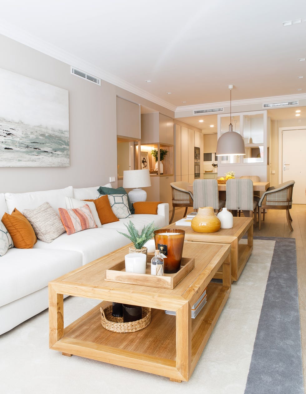 salón con sofá blanco, mesas de centro de madera y comedor