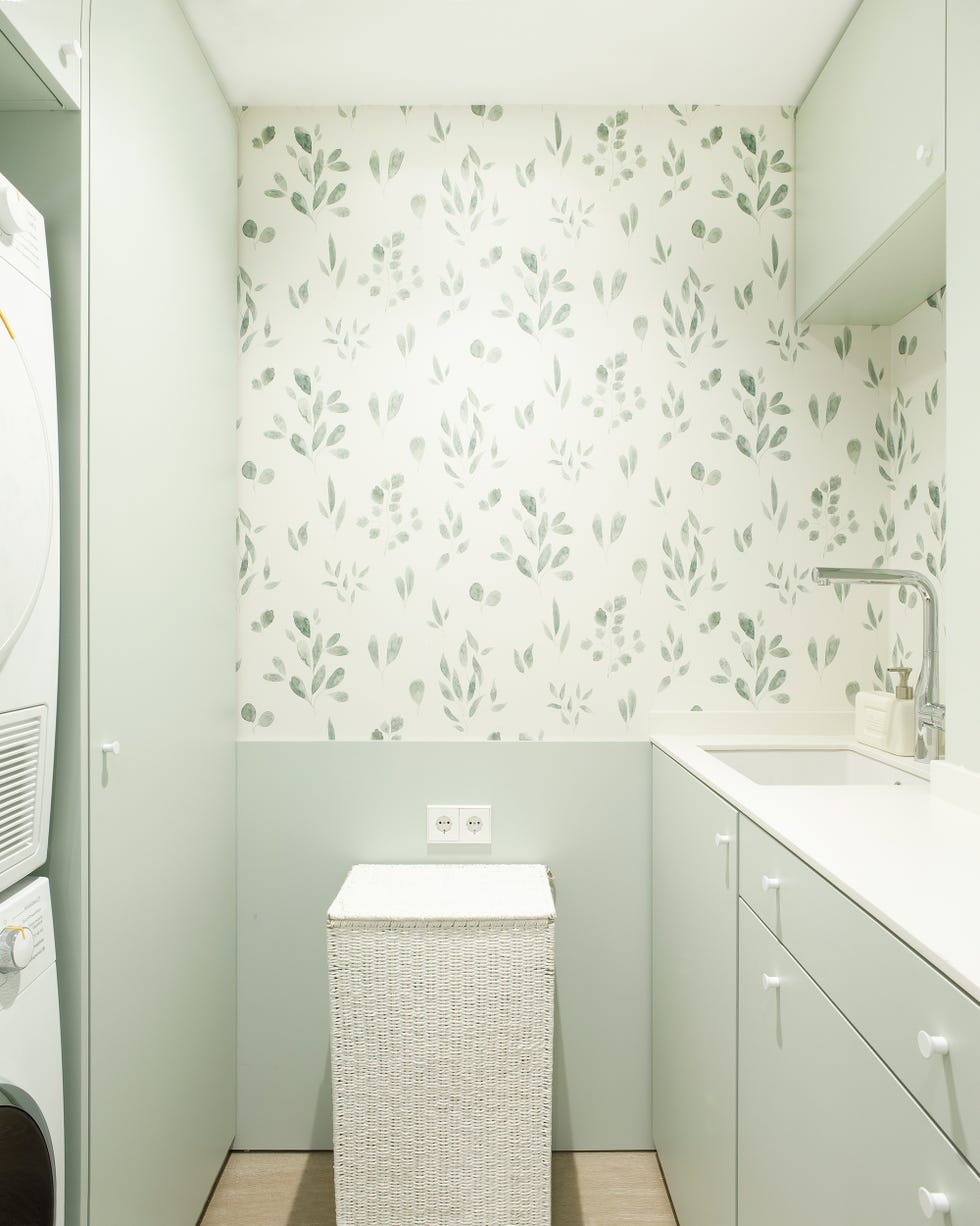 sala de lavandería con armarios verdes y papel pintado con motivos botánicos