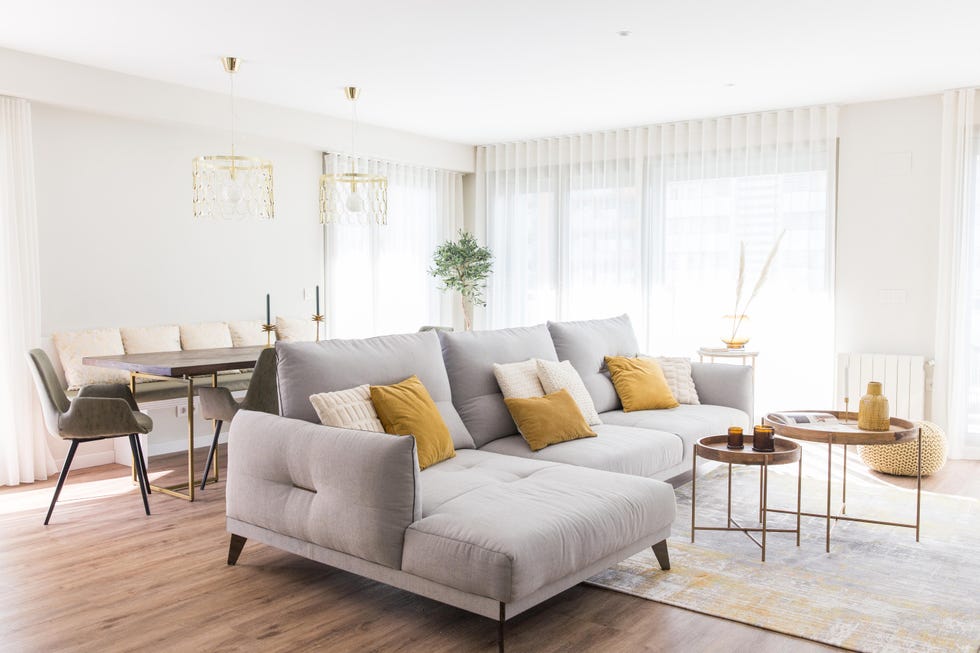 salón comedor con sofá con chaiselongue gris y mesas de centro redondas