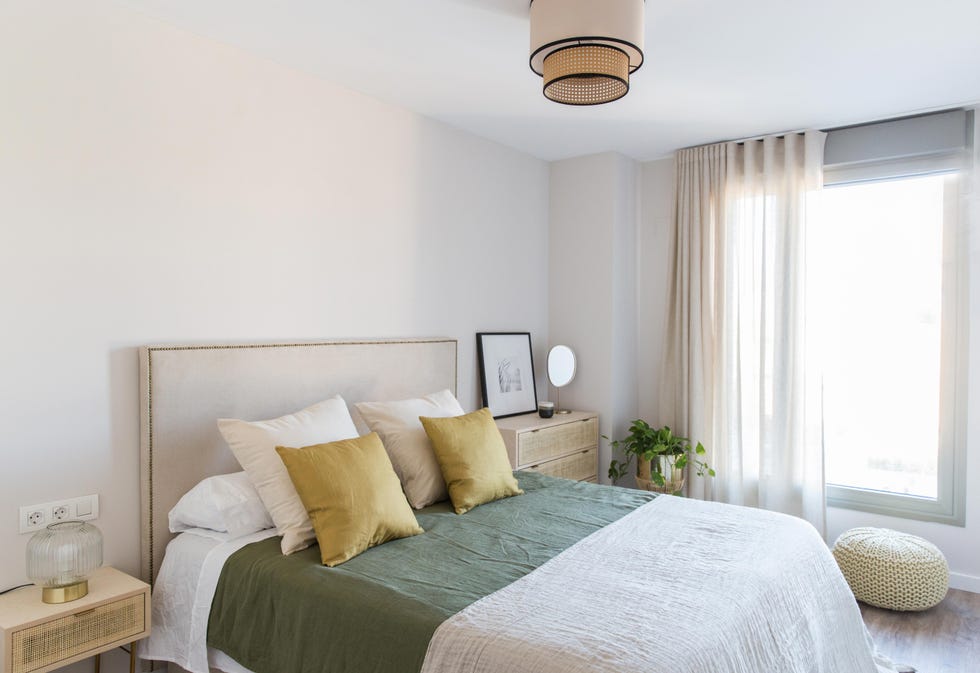 dormitorio con cabecero tapizado en lino, mesitas de madera y textiles verdes