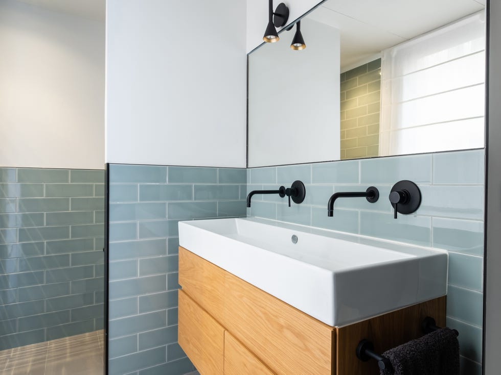 baño con mueble suspendido de madera y azulejos tipo metro azules