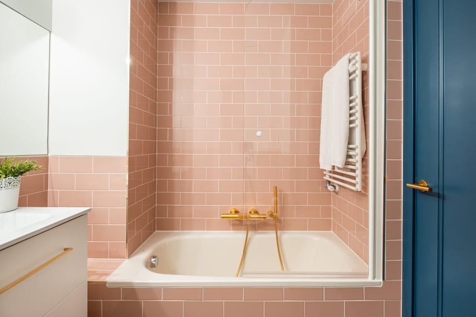 baño con bañera, azulejos tipo metro rosas y mueble blanco suspendido