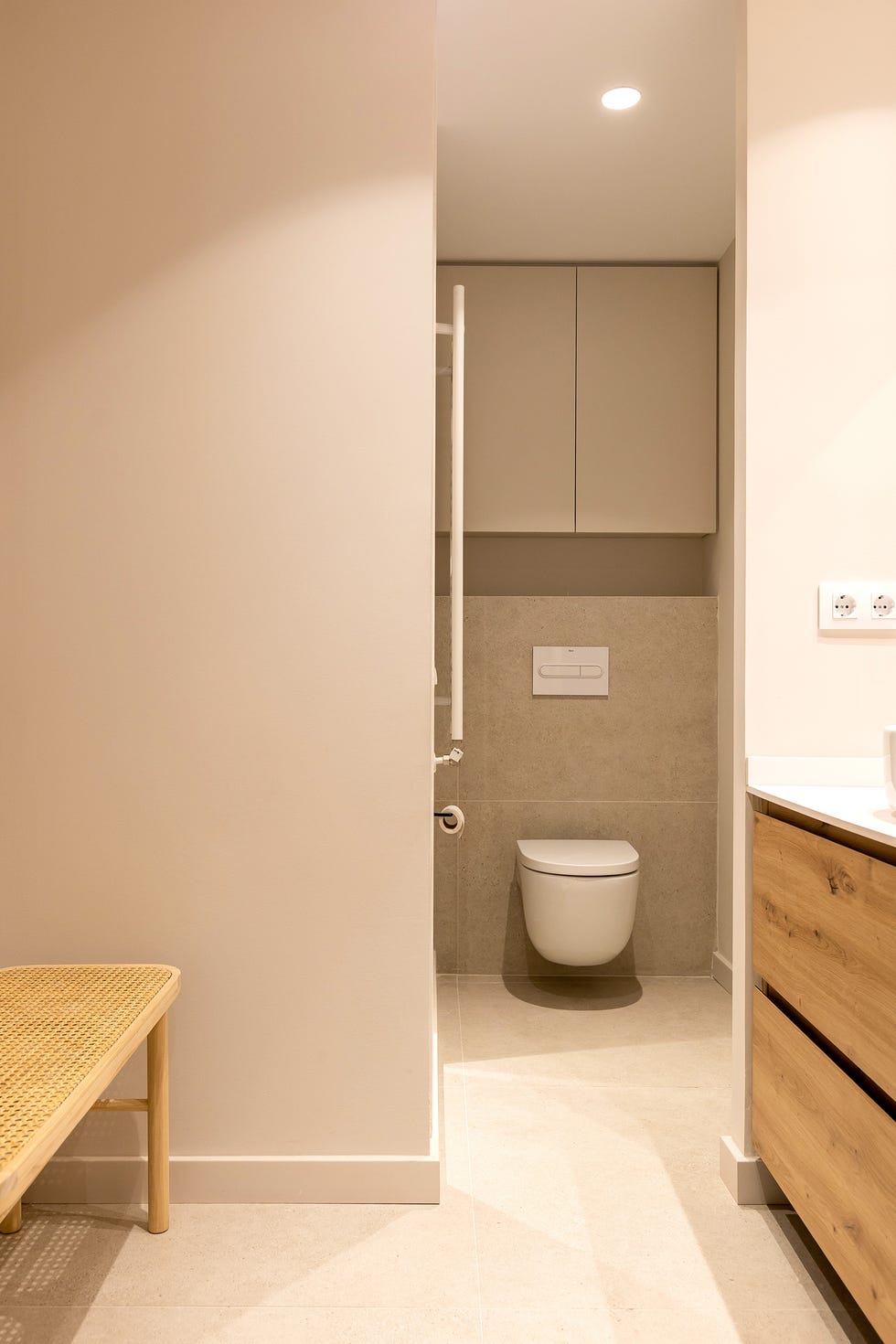 baño con mueble de lavabo de madera y banco de rejilla
