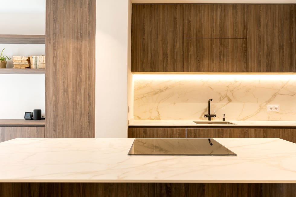 cocina con isla diseñada con madera y encimera de mármol