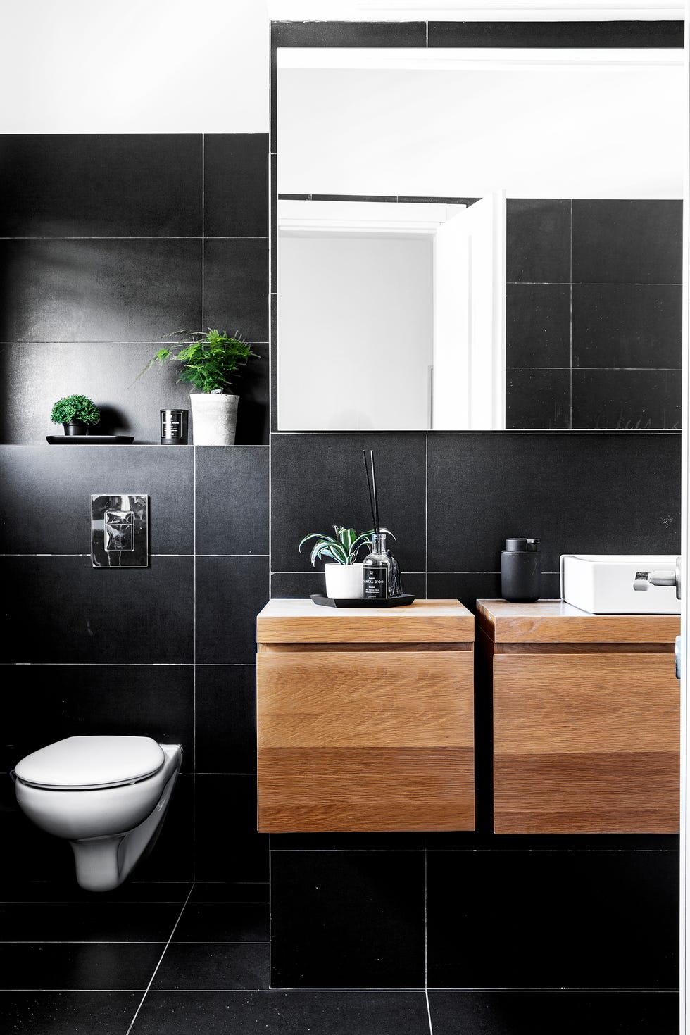 baño con azulejos en negro y mueble de lavabo de madera de roble
