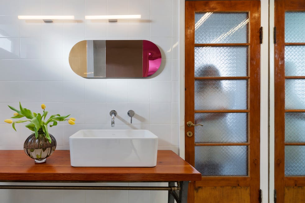 baño con mesa antigua de madera y pila de cerámica blanca