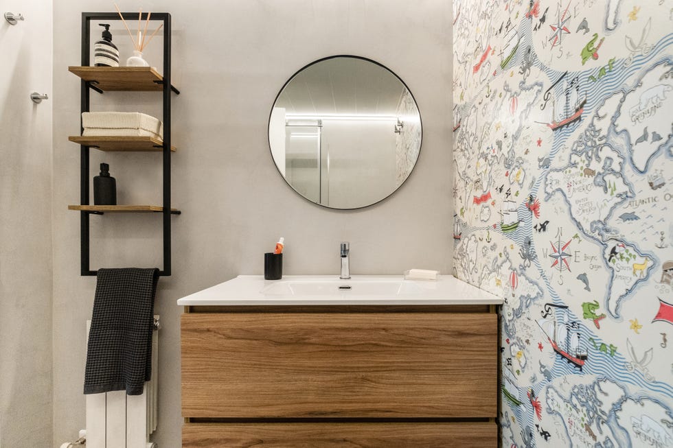 baño infantil con mueble de madera suspendido, estantería de pared industrial y papel pintado con un mapamundi