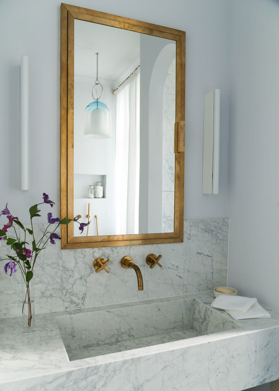 lavabo de mármol con grifo de latón a juego con el espejo