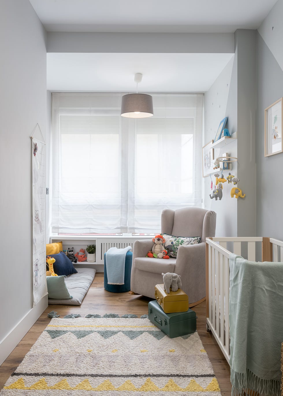 habitación infantil nórdica con cuna y butaca de lectura