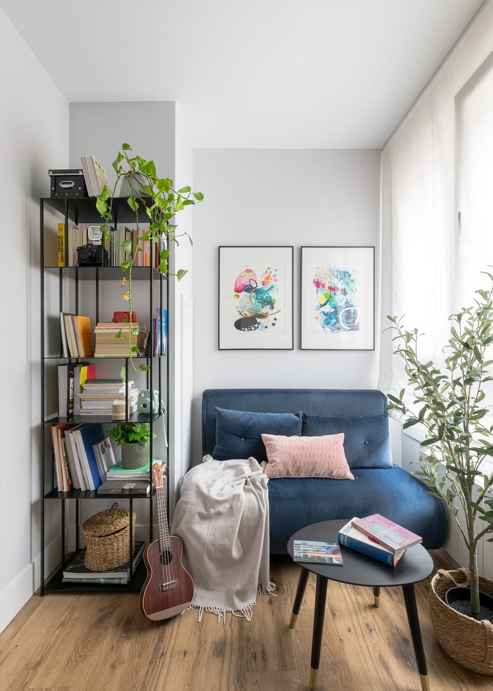 despacho con sofá cama de terciopelo azul y librería de metal negro