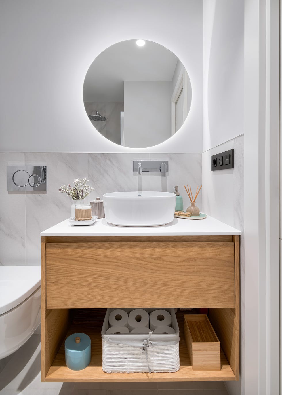baño con revestimiento de mármol y mueble bajo lavabo de madera suspendido