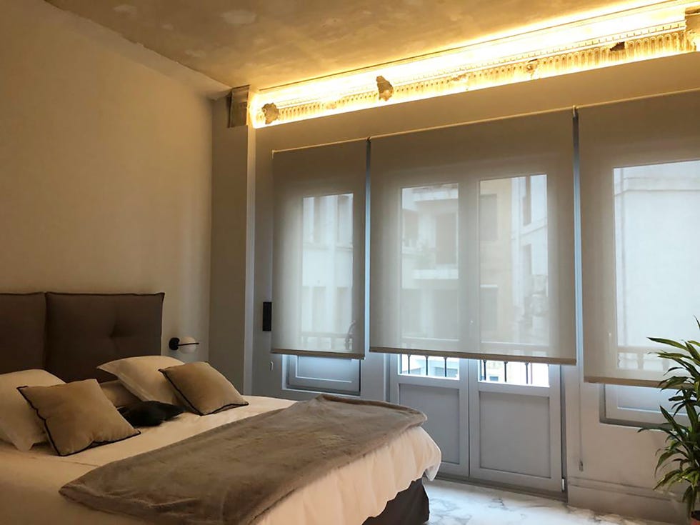 dormitorio decorado en tonos neutros con suelo de mármol y techo con moldura recuperada