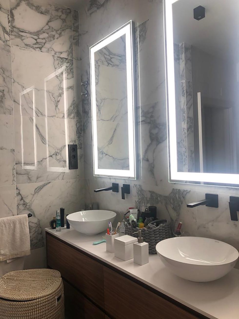 baño con paredes de mármol y espejos con iluminación led integrada