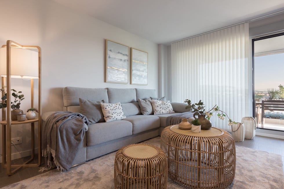 sofá gris con chaise longue y mesas de centro de ratán redondas
