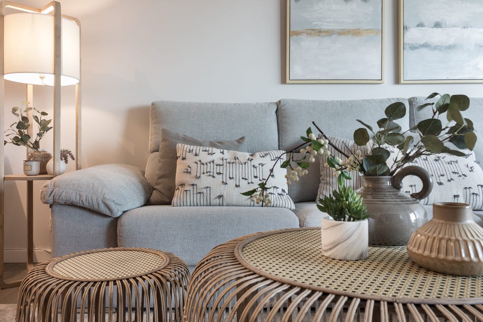 sofá gris con chaise longue y mesas de centro de ratán redondas