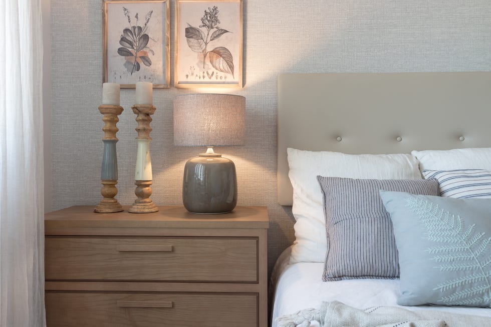 dormitorio con papel pintado efecto tejido en color beige y cabecero acolchado beige y mesitas de madera