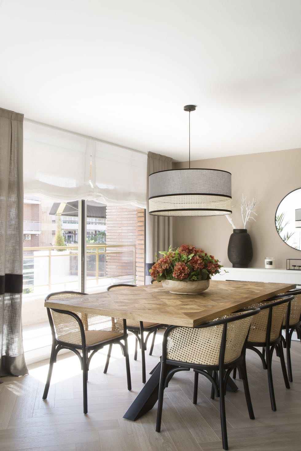 mesa de comedor de madera con patas de hierro y sillas de rejilla con lámpara suspendida