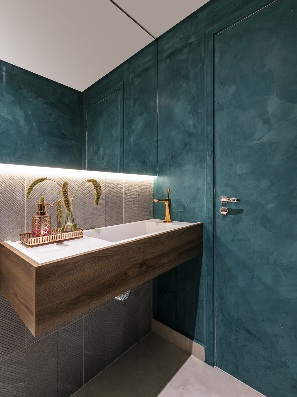 aseo con lavabo suspendido, paredes azules y revestidas con azulejos geométricos
