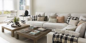salón moderno con sofá esquinero blanco, mesas de centro de madera y butaca reclinable