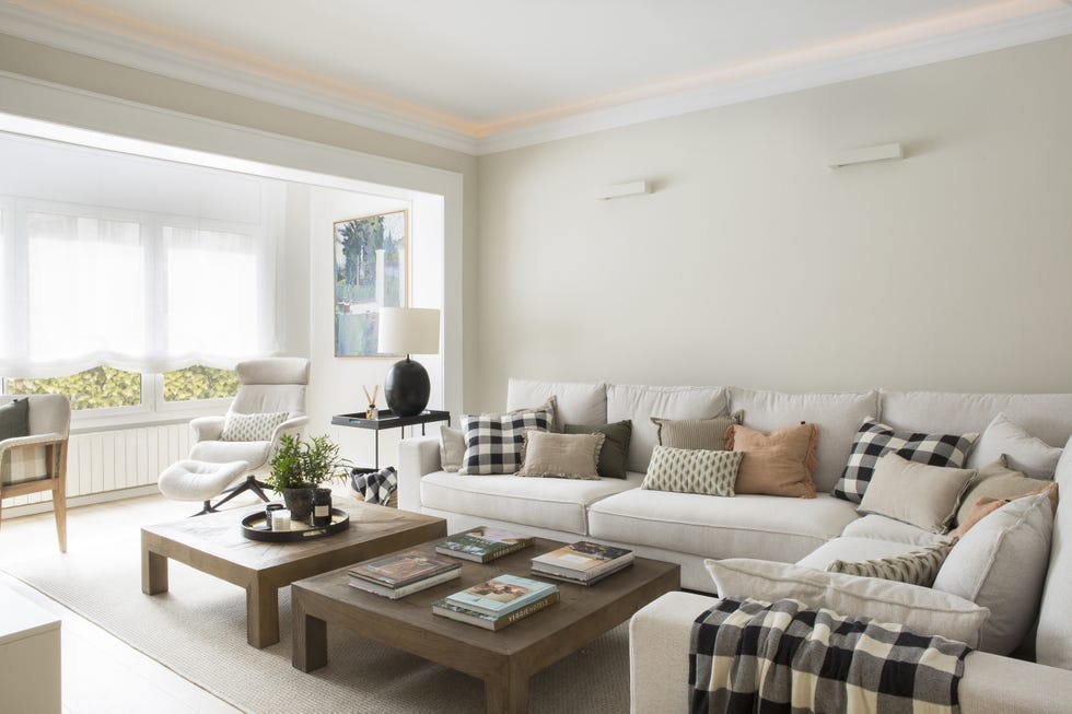 salón moderno con sofá esquinero blanco, mesas de centro de madera y butaca reclinable