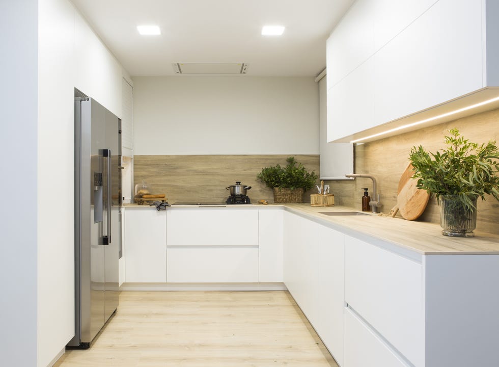 cocina moderna con armarios blancos sin tiradores y encimera y frente de madera